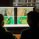 Two people look at a video screen with cows on it.